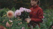Young Woman Carrying Bouquet Of Dahlia Flowers In Garden
