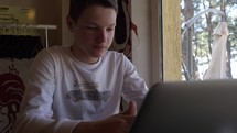Teenage boy typing on a laptop.