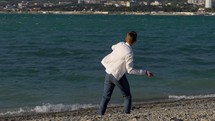 Guy throwing rocks into a body of water.