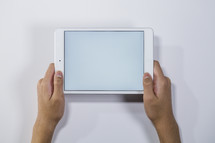 hands holding up a tablet 