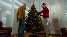 two boys are decorating the Christmas tree in the house