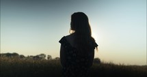 Silhouette of woman watching sunset on farm.