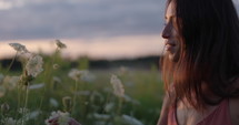 Woman smelling flowers at sunset - side profile - slow motion