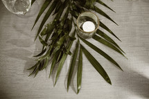 votive candle on palm fronds on a table 