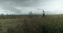 Young man walking on unpaved, dirt road on summer day explore, hiking, worshipping and praying. Lifestyle, worship and prayer concept.