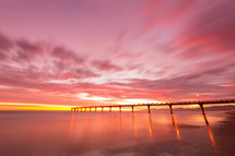 bridge over water under a pink sky at sunset 