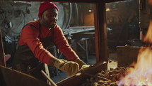 Black Man Heating Metal Billet in Forge Fire at Work in Smithy