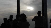 Silhouettes of a crowd of people, tourists, families, man and women at the top of the Burj Khalifa in cinematic slow motion.