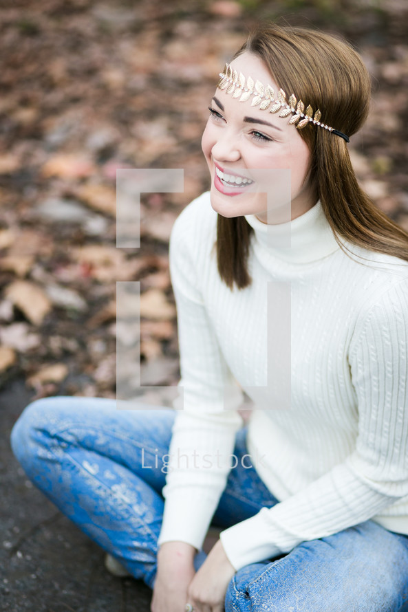 portrait of a smiling young with with a gold leaf headband 