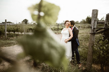 bride and groom standing in a vineyard 