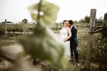 a bride and groom standing in a vineyard 