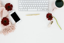 computer keyboard, nail polish, coffee mug, red gerber daisies, gold rings, white background, pink scarf, iPhone, pen