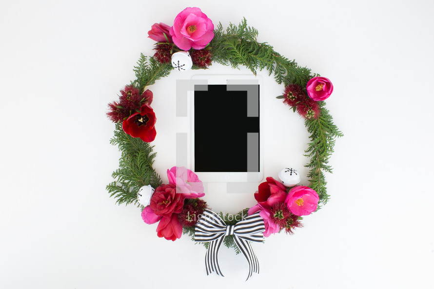 pine and flower wreath around an iPad 