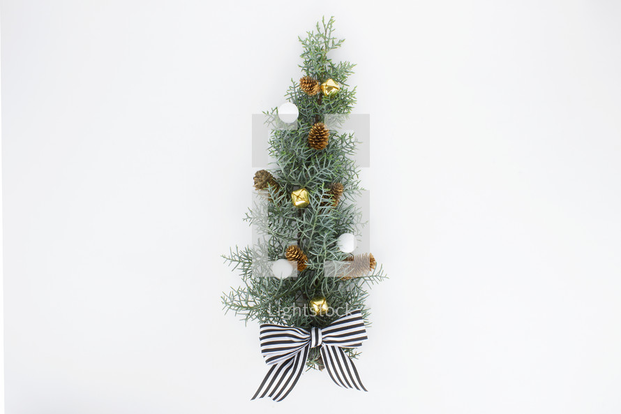 pine cones, bells, and bow on pine bough 