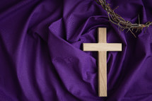 Cross and crown of thorns on a purple cloth background