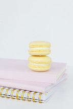 coffee and macaroons on a stack of pink notebooks