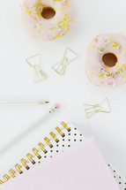 donuts, paperclips, notebooks, pencils on a white background 