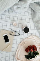 a sweater, roses, sheets, linens, bed, bedding, bedspread, iphone, planner, journal, pencil, reading glasses, candle, coffee mug, grid