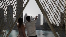 A couple, man and woman, tourists in Dubai pointing and looking up to sky at Burj Khalifa with distant buildings and skyscrapers at the Dubai mall in the middle east country of United Arab Emirates.