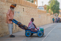 a man pushing his wife in a wagon India 