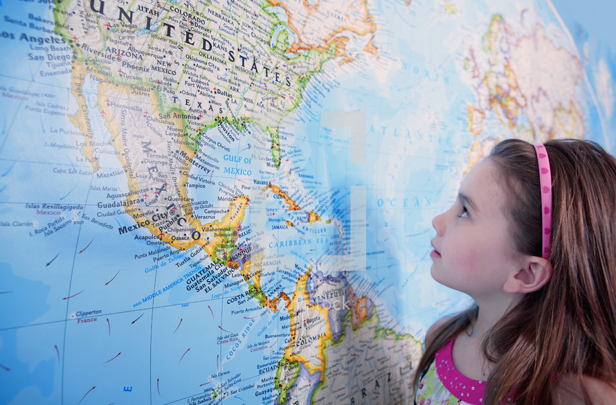 A young caucasian girl looking at the USA on a large map.- for editorial use only 