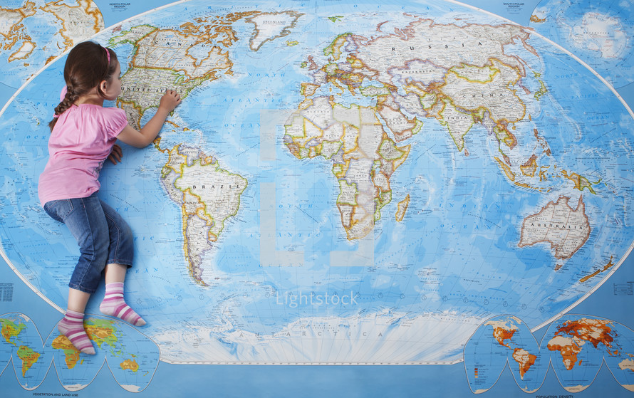 Top view of a young caucasian girl laying on a large map of the world- for editorial use only 