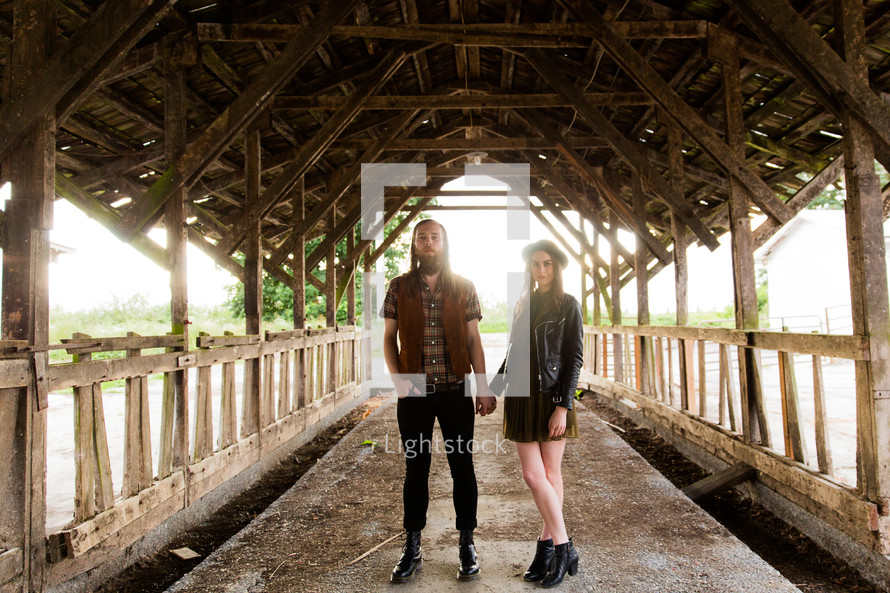 couple holding hands on a covered bridge 