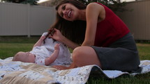Young mom kisses baby son while laying on grass