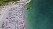 Aerial: Budva-Sveti Nikola Island, Montenegro: turquoise coastline with beach loungers