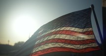 Sunset light shines on American, USA flag blowing in the wind in slow motion on 4th of July, Independence Day.