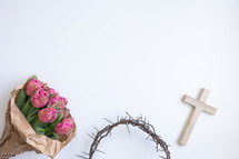 Border of crown of thorns, wood cross and bouquet of pink tulips on a white background