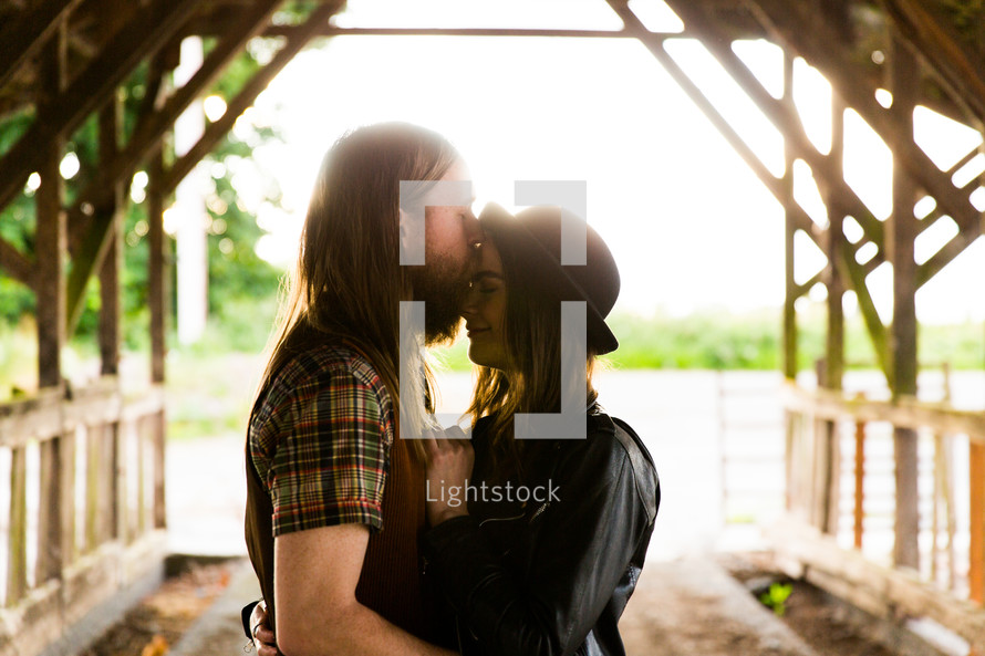 couple kissing under a covered bridge 