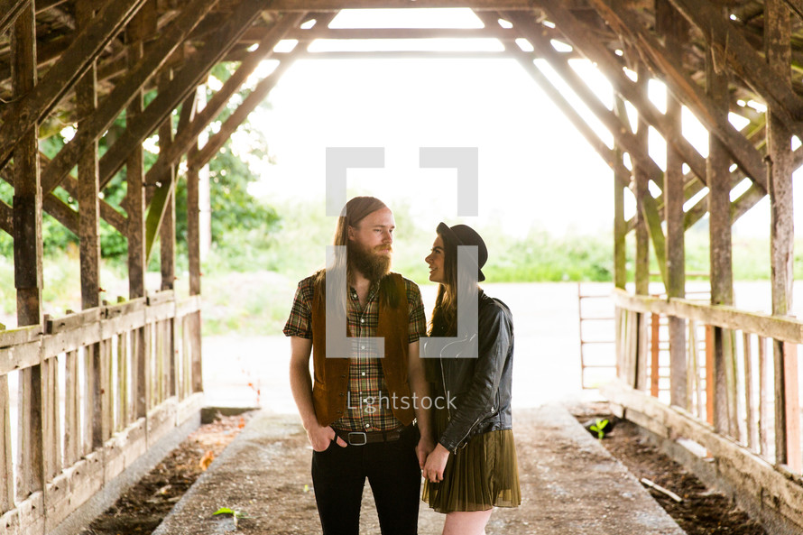 couple holding hands under a covered bridge 