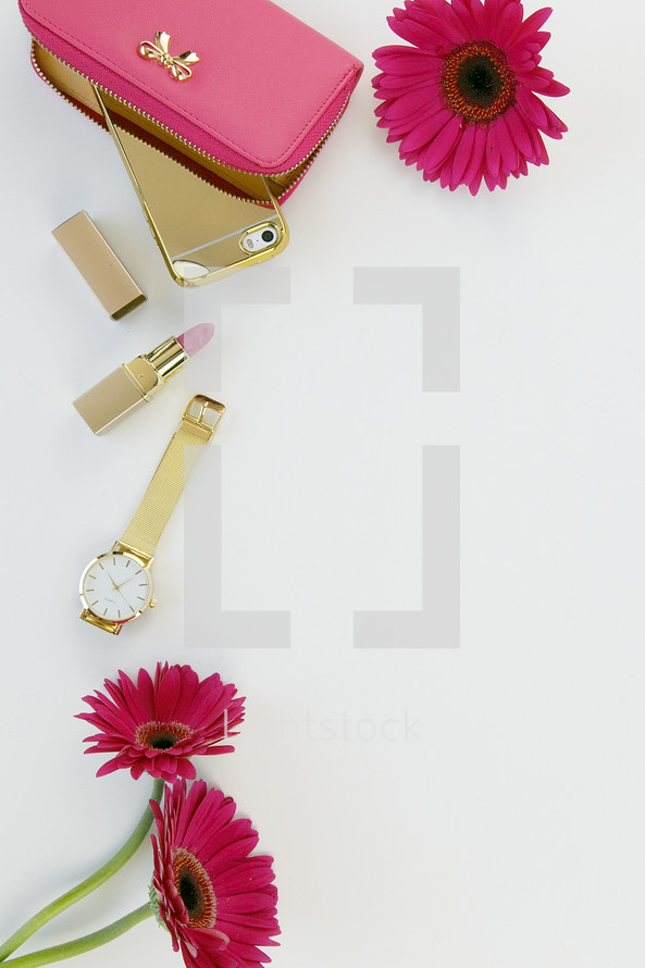 fuchsia gerber daisies, lipstick, gold watch, clutch, and cellphone 