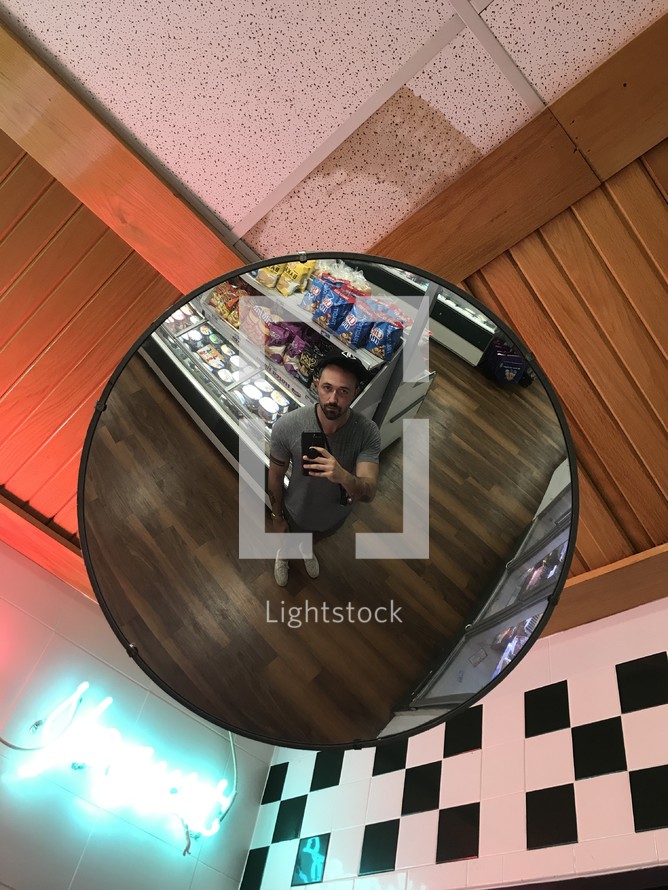 reflection of a man in a mirror in a convenience store 