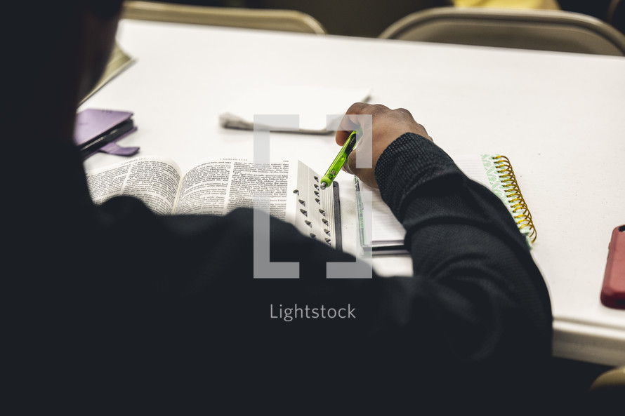 Man reading his Bible and taking notes on a table during a Bible study.