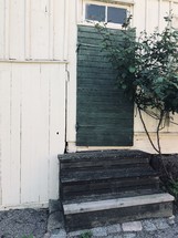steps leading to a rustic green wood door 