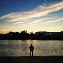 silhouette of a man standing in front of a lake