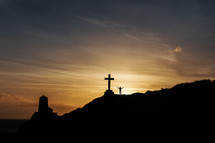 silhouette of a man standing next to a cross with open arms 