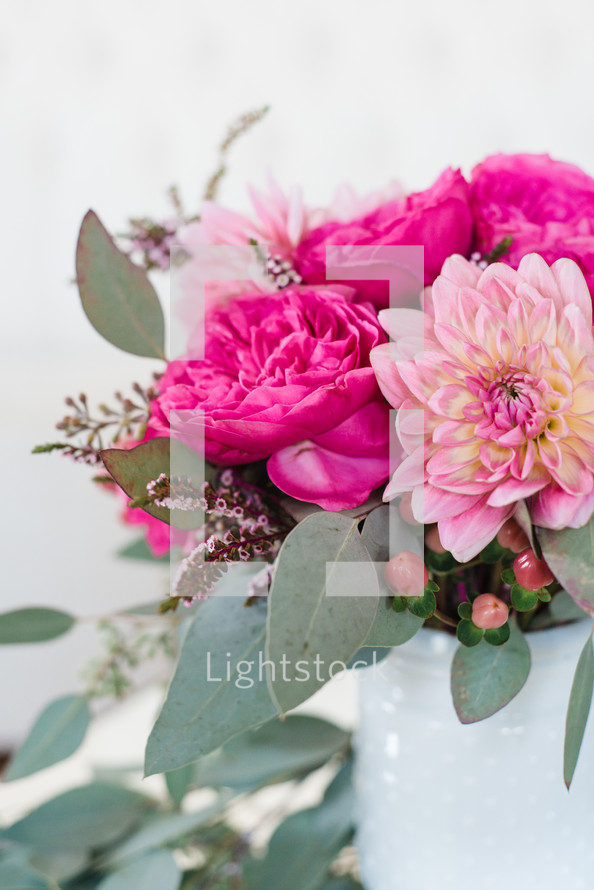 A bouquet of pink peonies in a white vase.