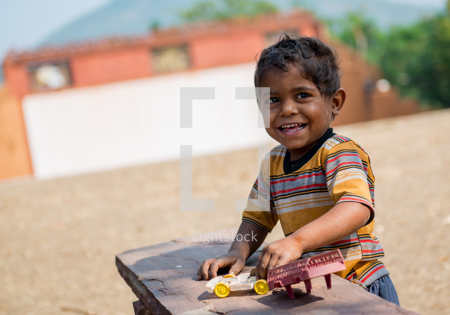 a boy playing with a toy car in India 