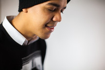 side profile of a man in prayer in a beanie 