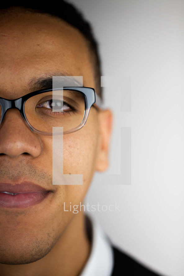 The face of a young man in glasses against a white background.