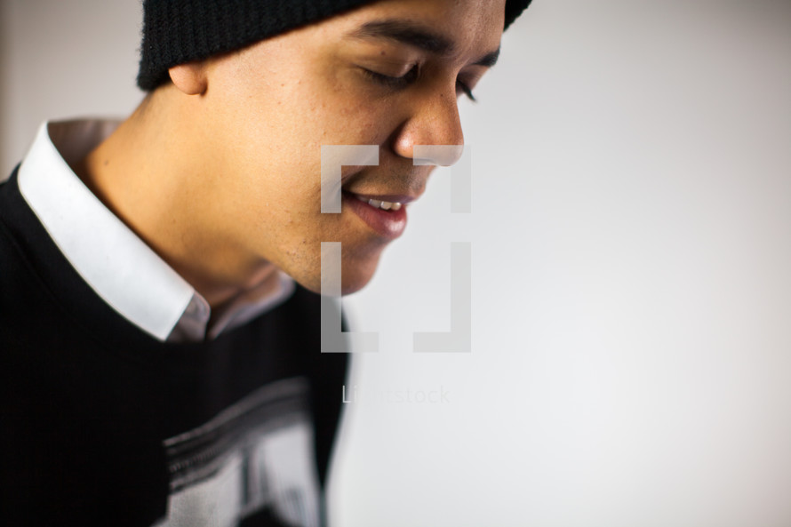 side profile of a man in prayer in a beanie 