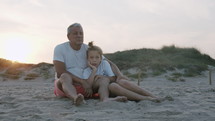 Grandpa and grandson on the beach at sunset