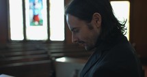 Young pastor in church with bible preaching, teaching sermon to congregation in Sunday morning worship service.