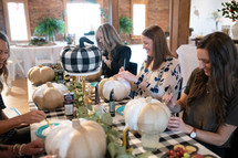 women gathered decorating pumpkins 