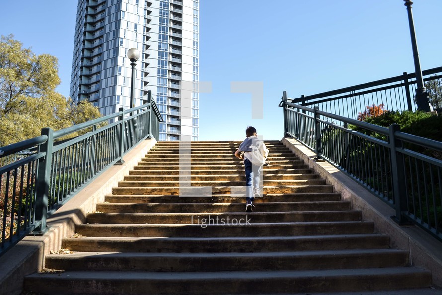 boy walking up outdoor steps in a city 