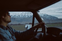 a man behind the steering wheel on a road trip 