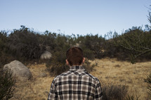 a man in a plaid shirt with his back to the camera 